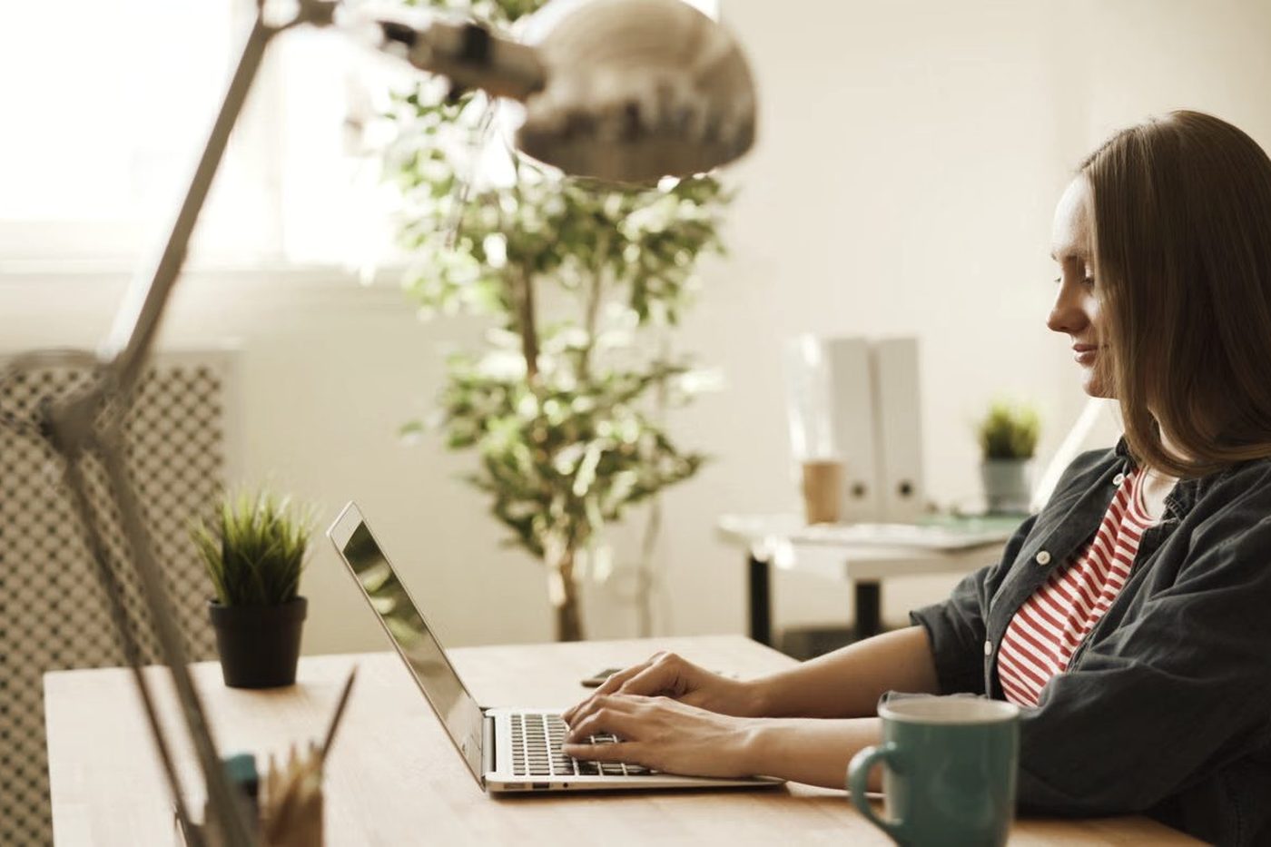 A teacher working at a laptop in a bright room