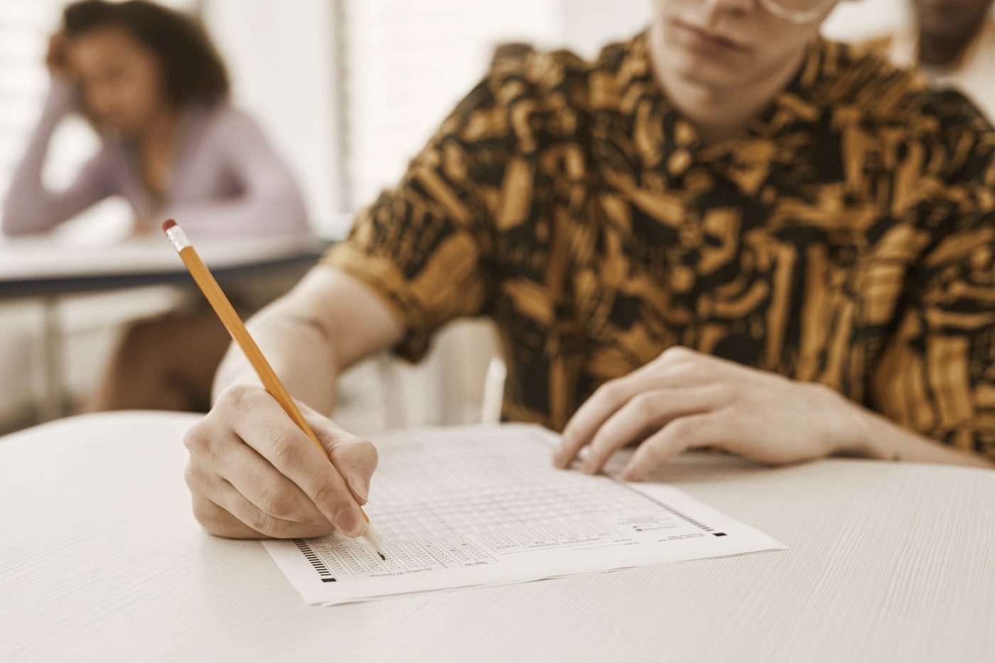 A student filling in a multiple-choice answer sheet in an exam room