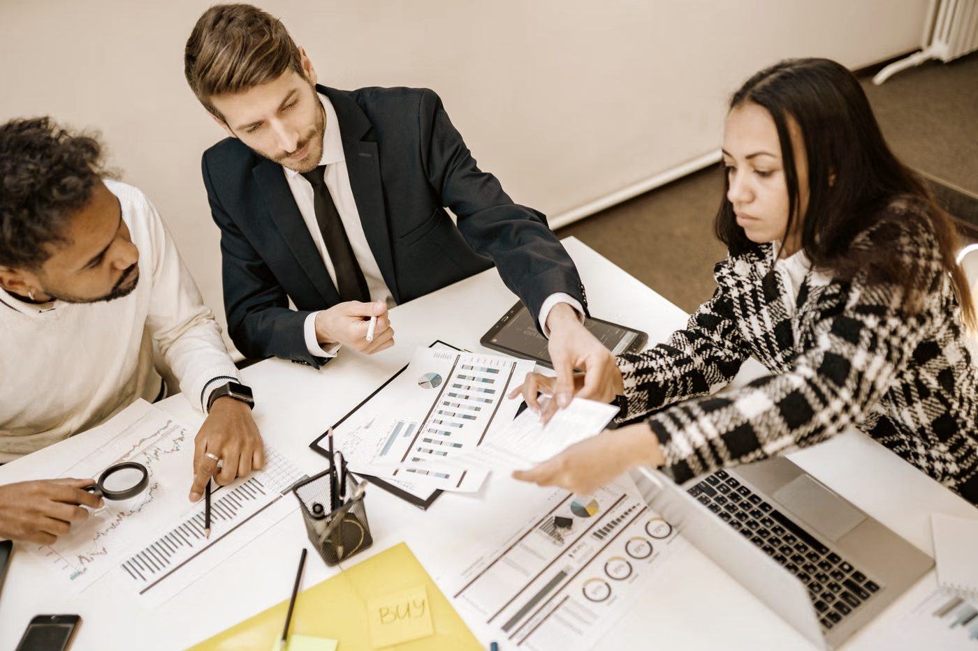 Colleagues around a meeting table reviewing charts and a laptop