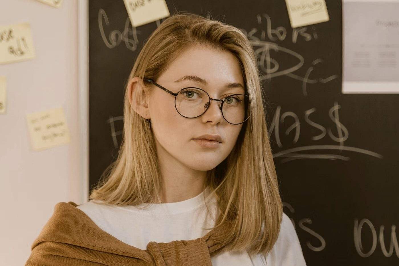 A teacher holding a tablet in front of a blackboard