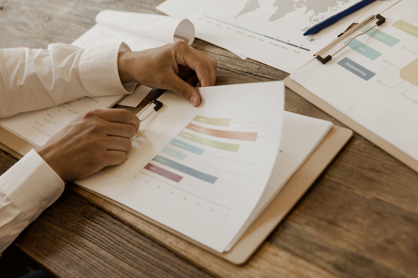 Hands reviewing a printed report with coloured markers on a desk