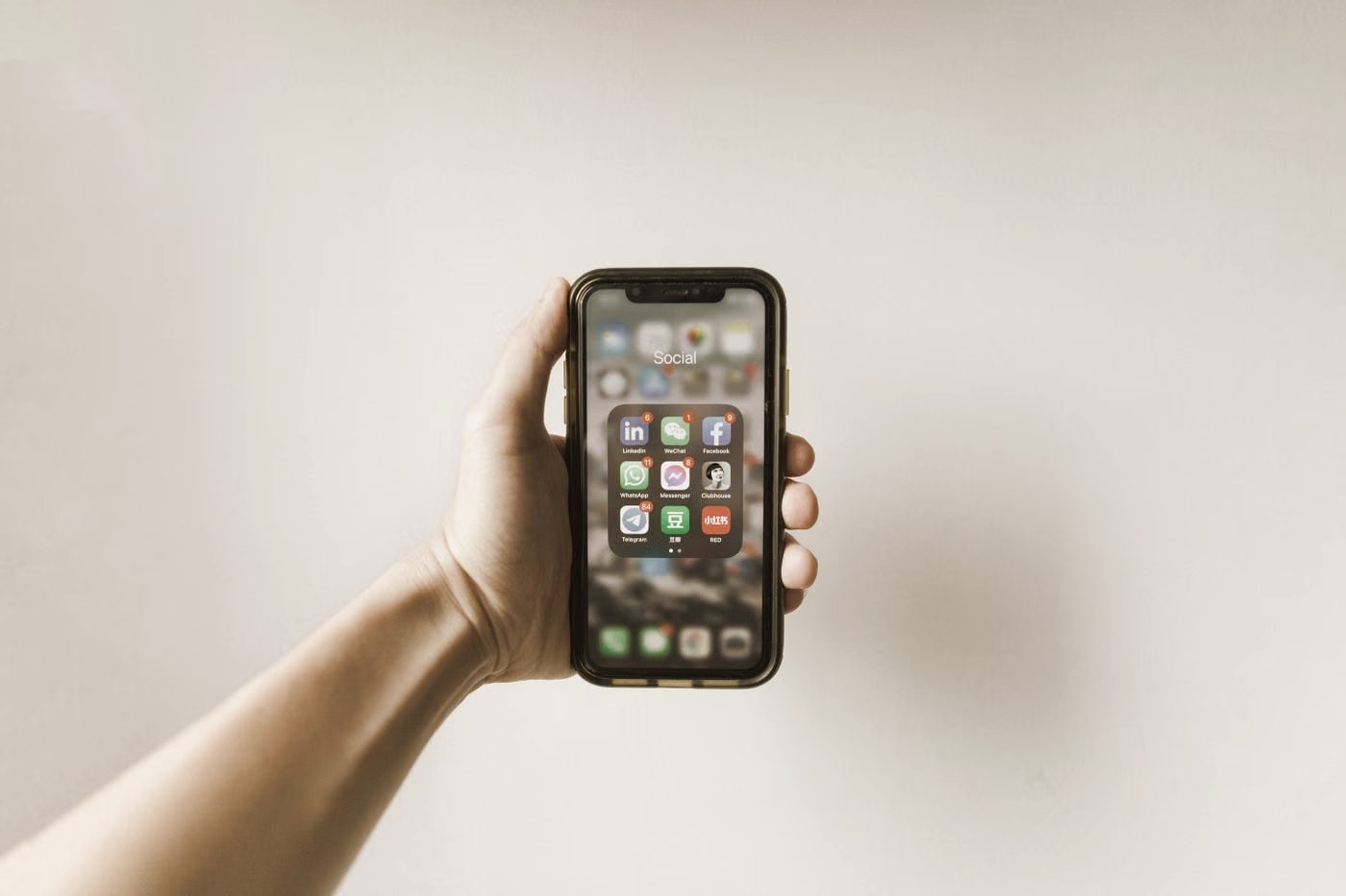 A hand holding a smartphone showing a grid of apps